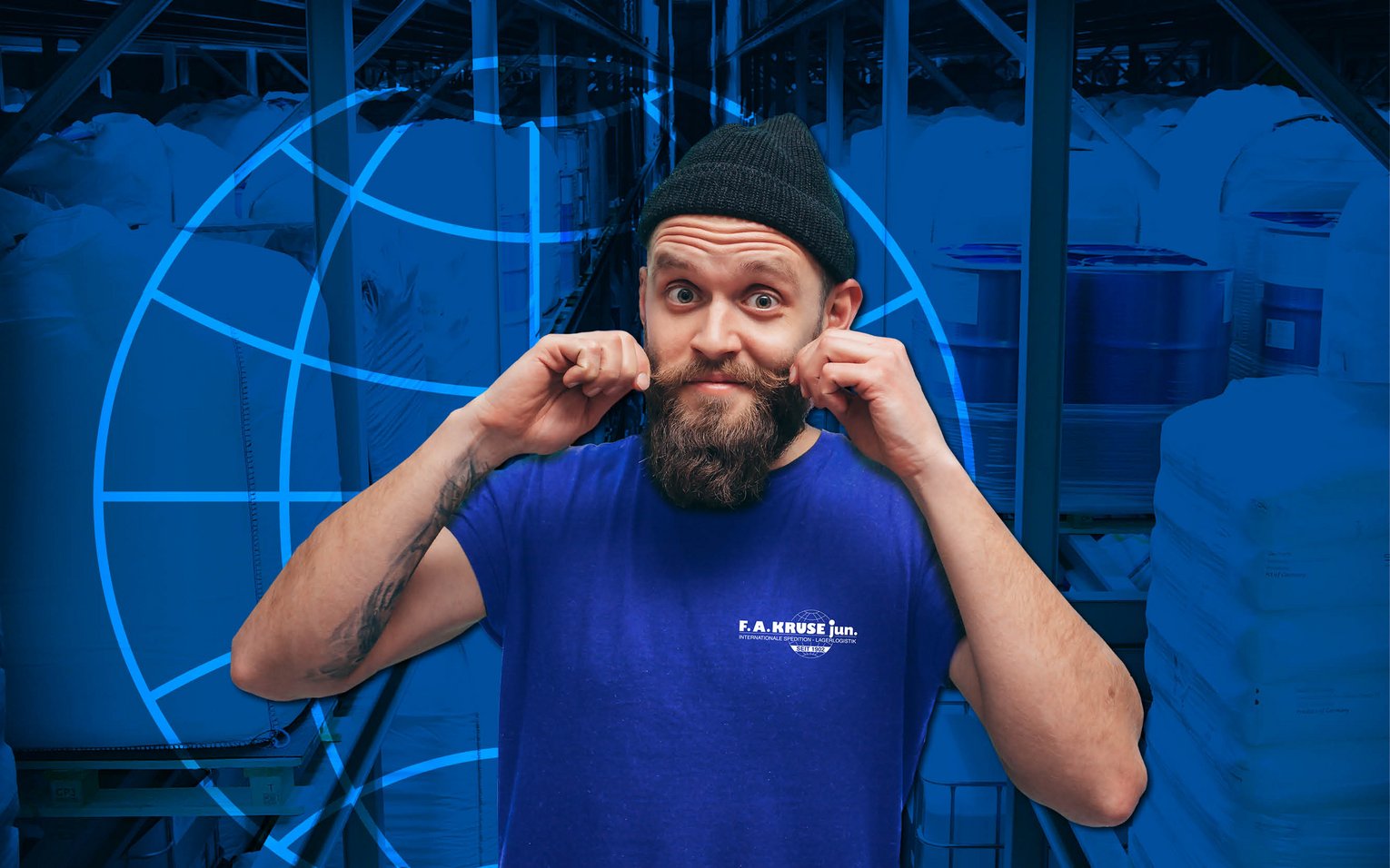Mitarbeiter von F.A. Kruse jun. mit Bart und Mütze im Lagerbereich, lächelnd und am Schnurrbart drehend.
