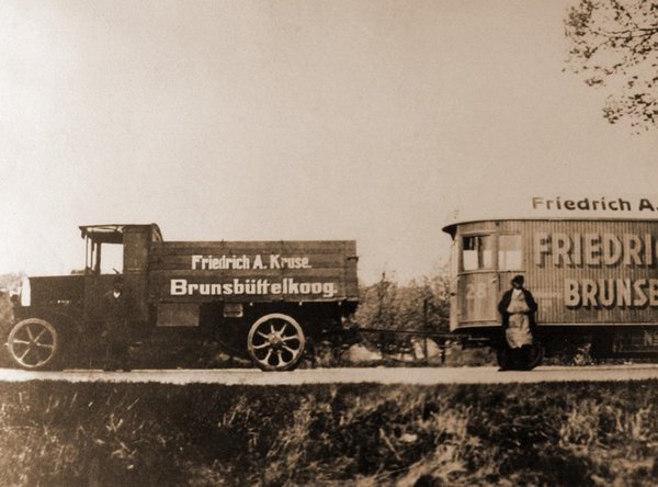 Historische Zugmaschine mit Anhänger von Friedrich A. Kruse, zwei Personen steht daneben.