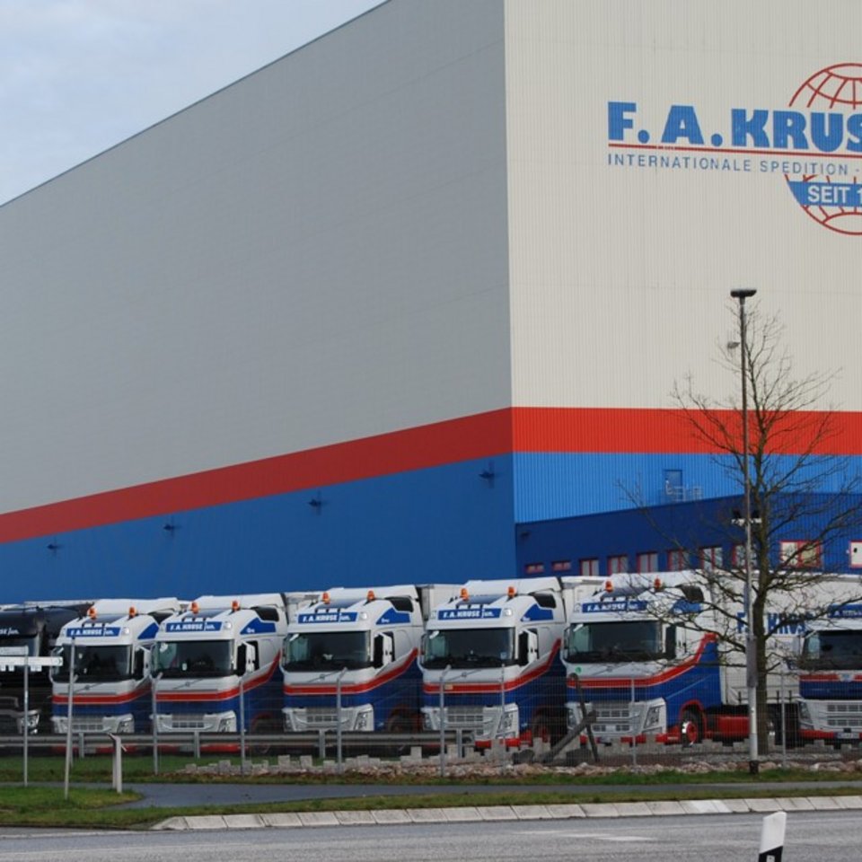 Breite Ansicht der Kruse-Lagerhalle mit aufgereihten Lkw davor