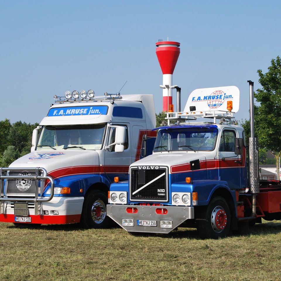 Zwei Lkw der Spedition Kruse auf einer Wiese, daneben roter Ballon mit Kruse-Logo