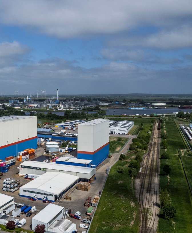 Logistikzentrum mit Hochregallagern und Gleisanschluss Luftaufnahme eines modernen Logistikzentrums mit Hochregallagern, Gleisanschluss und Fluss im Hintergrund.